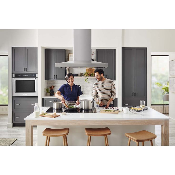 two people preparing food in a kitchen with gray cabinets