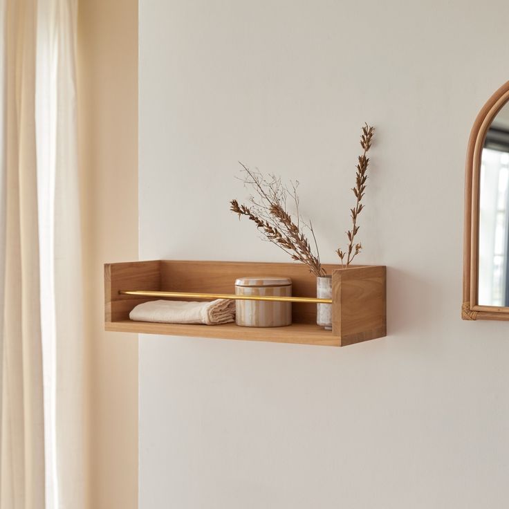 a wooden shelf with two jars and a mirror on the wall next to a window