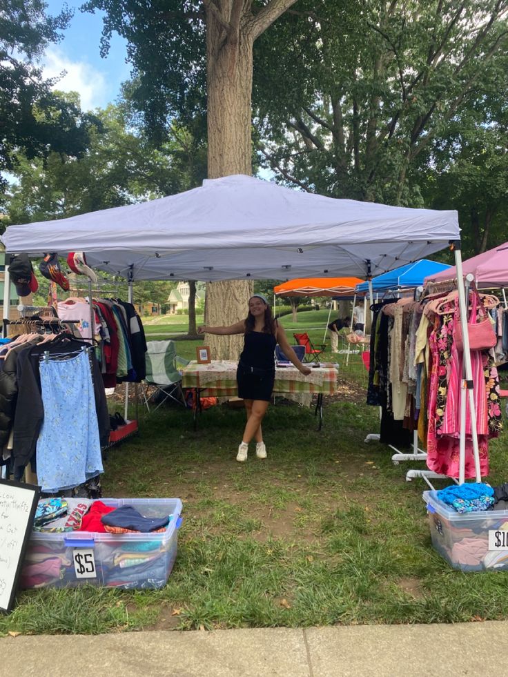 a woman standing under a tent with clothes on it