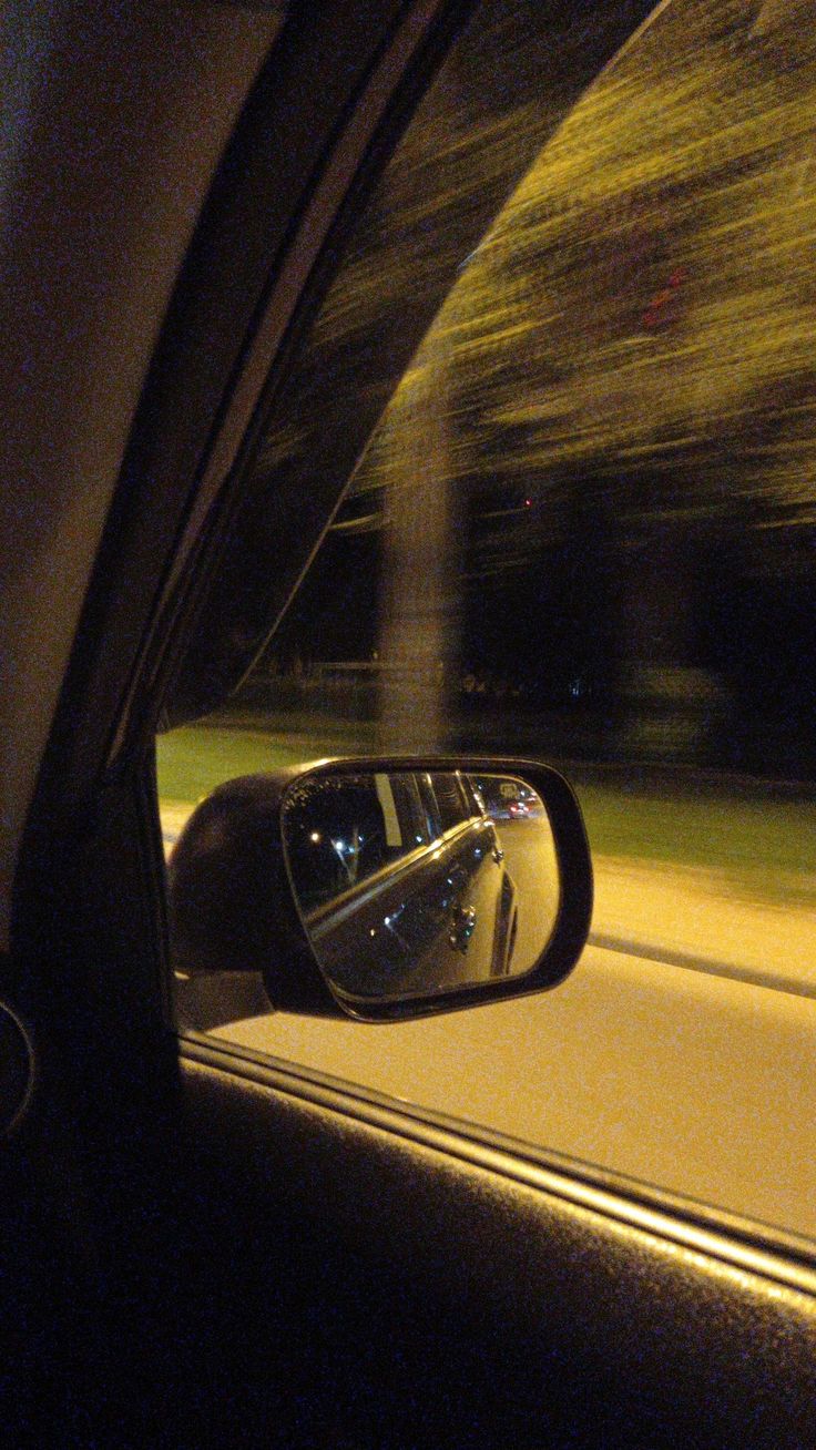 a car's rear view mirror with trees in the background