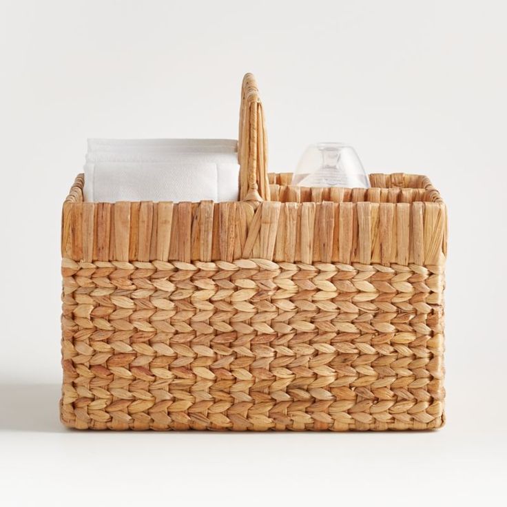 a woven basket with two napkins and an empty bottle in it on a white surface