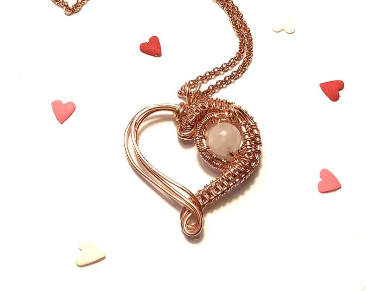 a heart shaped pendant is shown on a white surface with hearts scattered around the necklace