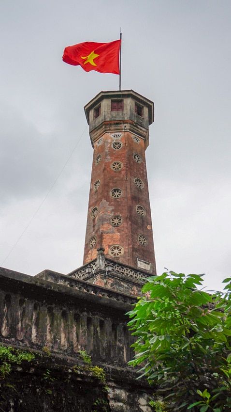 a red flag flying on top of a tall tower with a clock at the top