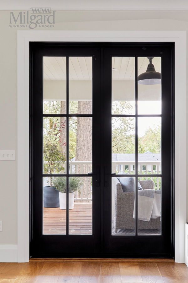 a black double door with glass and wood flooring in front of a white wall