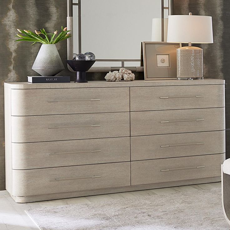 a dresser with a mirror, lamp and vase on it in a living room setting