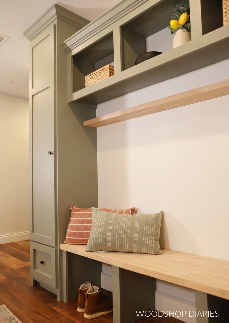 a wooden bench sitting in front of a white wall next to a shelf with baskets on it