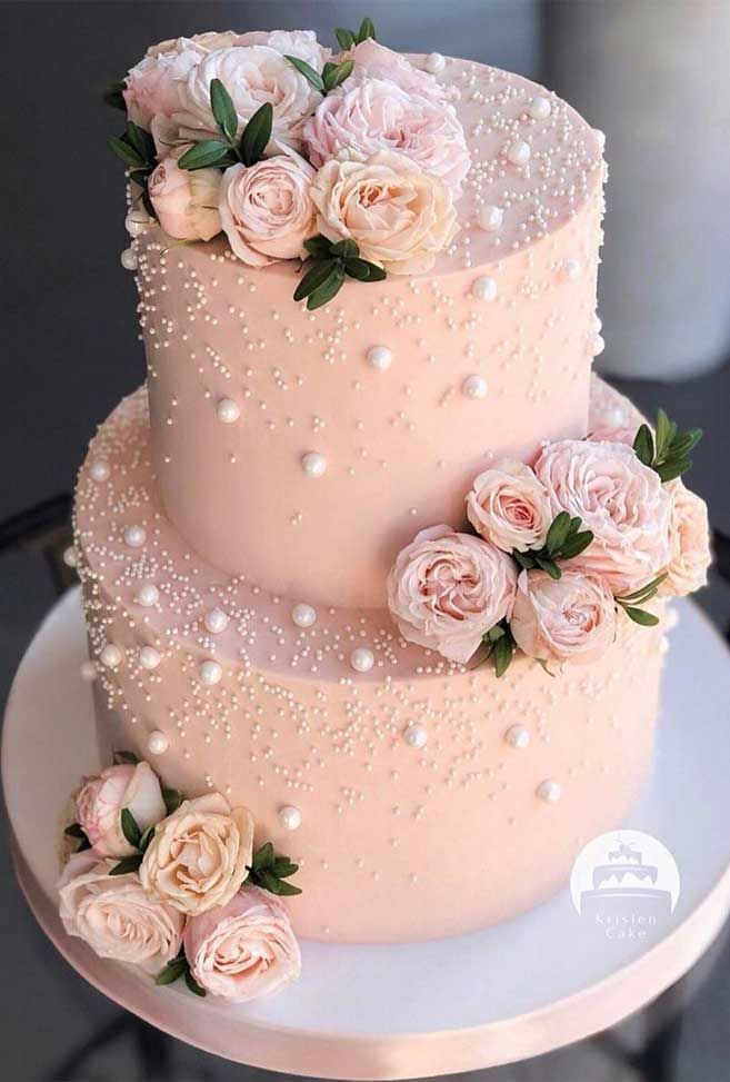 a three tiered cake with pink flowers on top and red roses around the edges