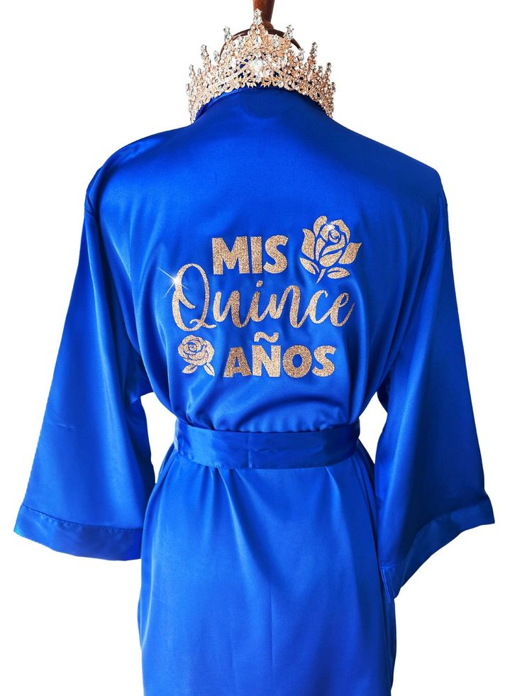 "Get ready for your Mis Quince Años celebration in style with our Quinceañera Satin Robes!  Crafted from soft and silky high-quality satin, these robes are designed to make you feel like a princess on your special day. With different options for text color and designs on the back side, you can customize your robe to match your unique style and personality. Not only are these robes perfect for getting ready, but they're also ideal for Instagram and Pinterest photos. Order yours Mis Quince robe to Dresses For Damas Quinceanera, Royal Blue And Gold Quince, Quince Robe, Royal Blue Quinceanera Decorations, Quinceanera Royal Blue, Royal Blue Quinceanera Theme, Blue Quince Dress, Blue Quinceanera Theme, Crown And Tiara