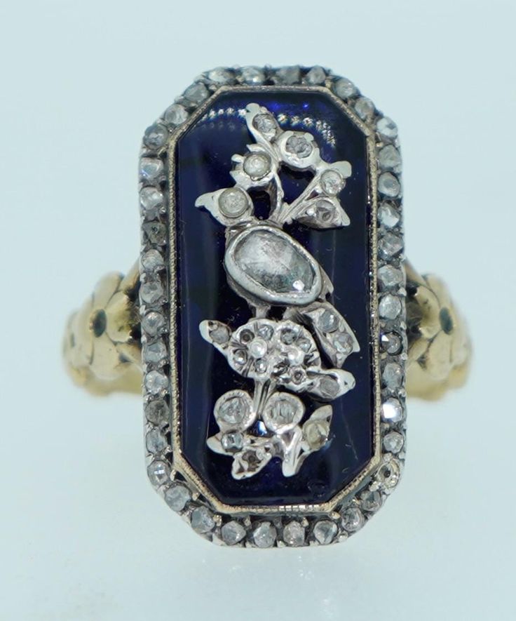 This is an exceptional original Georgian Era ring. It dates from the 1800s. It is crafted from solid 18K as well as sterling silver and natural rose cut diamonds. The underlying bristol blue glass is in wonderful condition, a couple of very very minor knicks on the edge. Pinned on to the top of the Bristol glass is a lovely bird perched on a floral branch. The bird is done in sterling silver and adorned with fine rose cut diamonds of various sizes. The diamonds are in good condition, a couple of very small diamonds missing on the branch area (not noticeable unless magnified). The boarder of this ring is covered in a frame of additional rose cut diamonds set in silver. The shoulders of this ring feature flowers. The shank and back of the ring are testing as solid 18K yellow gold (not hallma Victorian Blue Jewelry With Diamond Accents, Antique Diamond Intaglio Jewelry, Antique Blue Rings With Rose Cut Diamonds, Victorian Blue Rings With Rose Cut Diamonds, Vintage Blue Ring With Single Cut Diamonds, Vintage Blue Single Cut Diamond Rings, Vintage Blue Rings With Single Cut Diamonds, Bird Ring, Bird Rings