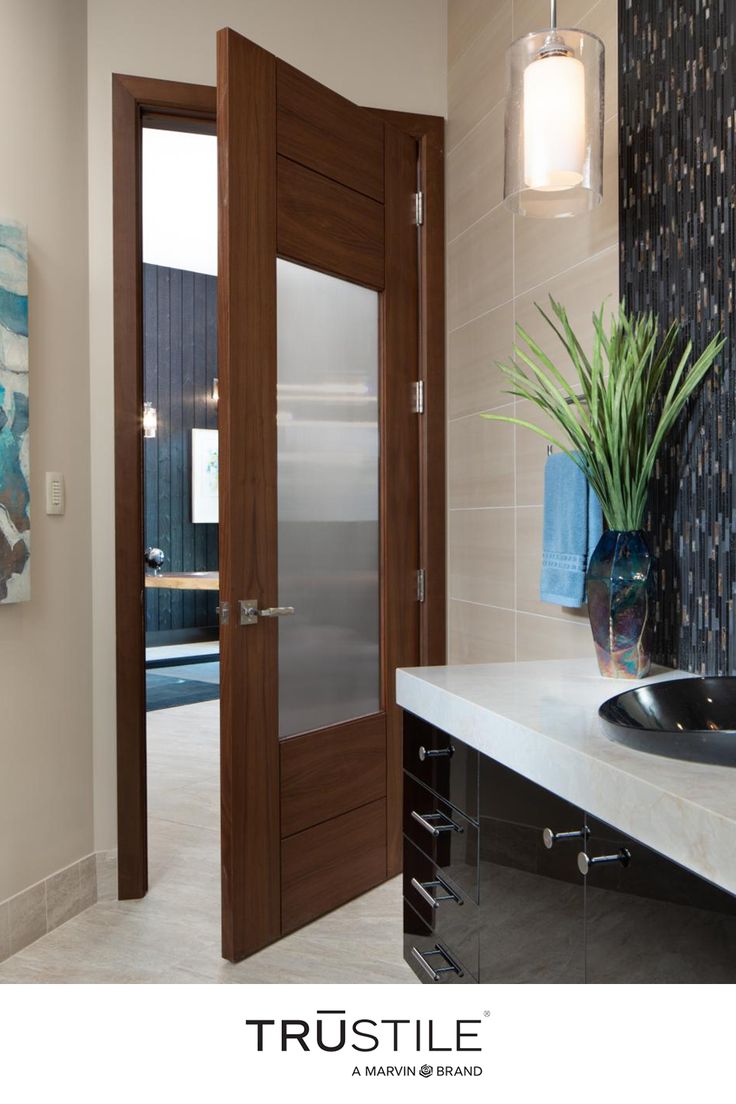 a bathroom with a sink, mirror and wooden door in the wall next to it