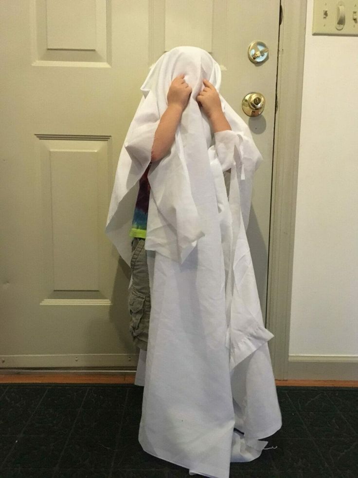 a young boy wrapped in white paper standing next to a door