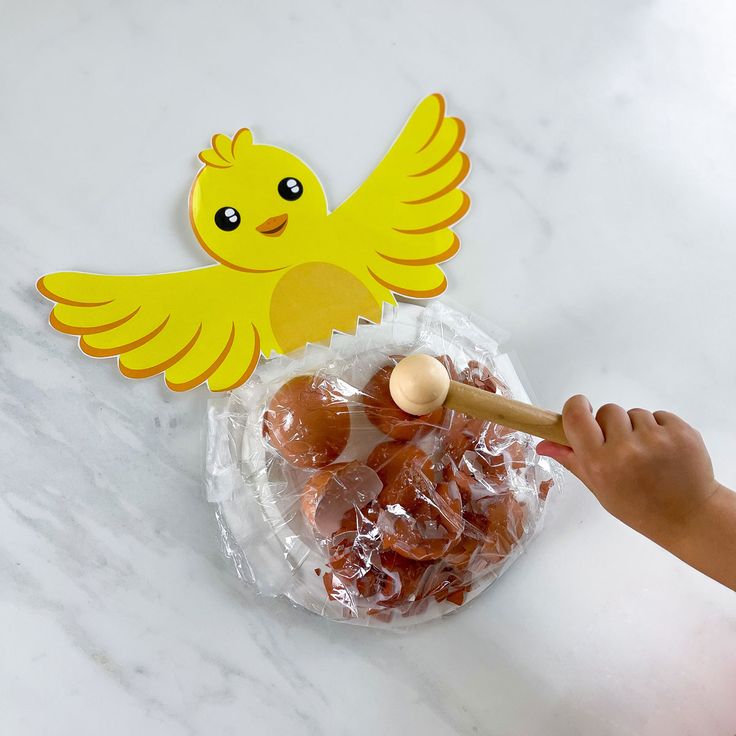 a child's hand holding a wooden spoon in front of a bag of candies