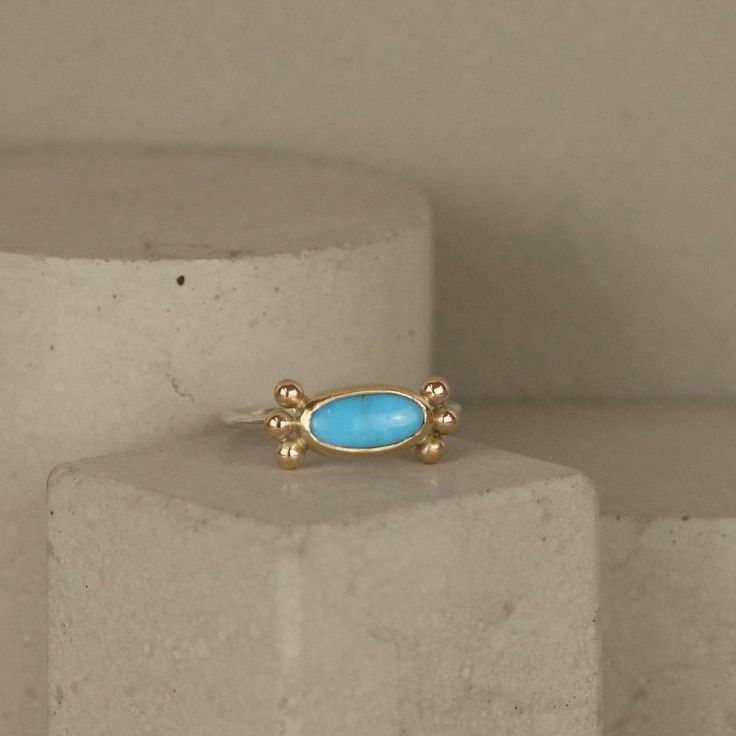 Pretty little turquoise oval gemstone is set in a 9ct yellow gold bezel and decorated in 9ct gold studs. Backed in sterling silver and on a silver band. One of a kind ring in size O though I have a couple of other small turquoise cabochons similar to this that I can make a ring in your size with. 15mm x 6mm on top (including studs) Official UK hallmarks are applied by the London Assay Office. 5% of all profits are donated to the refugee charity Choose Love Gold Oval Hallmarked Turquoise Ring, Gold Hallmarked Turquoise Ring Fine Jewelry, Gold Turquoise Ring Hallmarked Fine Jewelry, Gold Oval Turquoise Sterling Silver Ring, Oval Gold Turquoise Ring Gift, Gold Oval Turquoise Ring Gift, Fine Jewelry Turquoise Ring In Yellow Gold, Oval Gold Turquoise Ring In Sterling Silver, Gold Oval Turquoise Ring In Sterling Silver