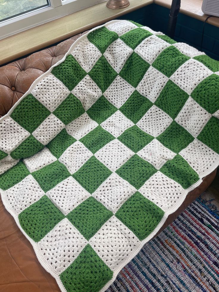 a green and white crocheted blanket sitting on top of a couch