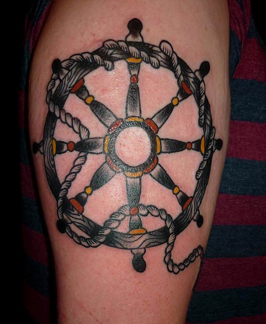 a man's arm with a ship wheel and rope tattoo on the side of his arm