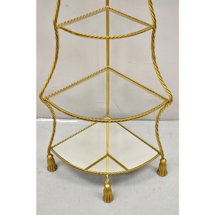 a three tiered gold metal shelf with tassels on the top and bottom