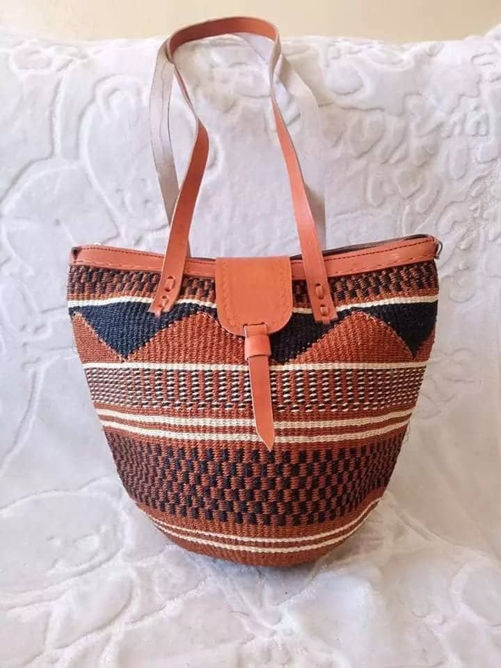 Tote bag, Woven Bag with Leather Handles, Beach Bag, Picnic Bag, Natural Bag, laptop bag, Office bag, Traveling bag This beautiful handmade tote bag originated from craftsmen living in Eastern Community in Kenya, the Akamba. Our Tote bags are woven using colored sisal and leather hands.The woven bag is made from products which are entirely eco-friendly and sustainable, leather to provide comfort and padding. Leathers are naturally tanned from cows and camel. It has a zipper. This Tote bag is rea Handwoven Bucket Tote Bag For Daily Use, Brown Woven Bucket Bag, Daily Use Basket Bucket Bag With Leather Handles, Leather Handle Basket Shoulder Bag For Travel, Handwoven Tote Bucket Bag, Handwoven Bucket Bag For Everyday Use, Travel Bucket Bag Handwoven, Everyday Woven Basket Bucket Bag, Bucket Bags With Braided Handles For Market