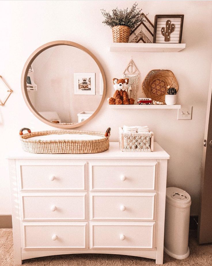 a white dresser with a round mirror above it