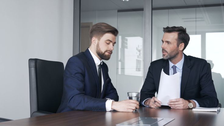 two men in suits sitting at a conference table