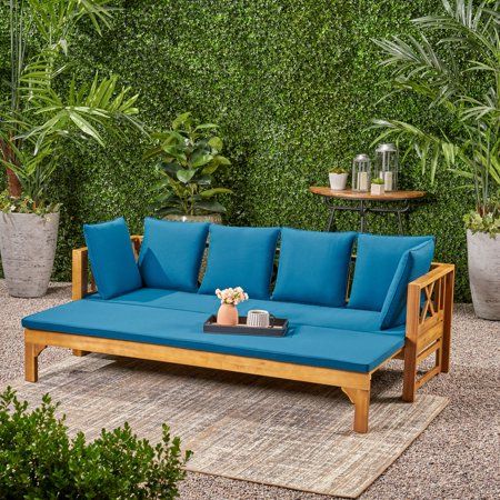 a blue couch sitting on top of a patio next to potted plants and greenery