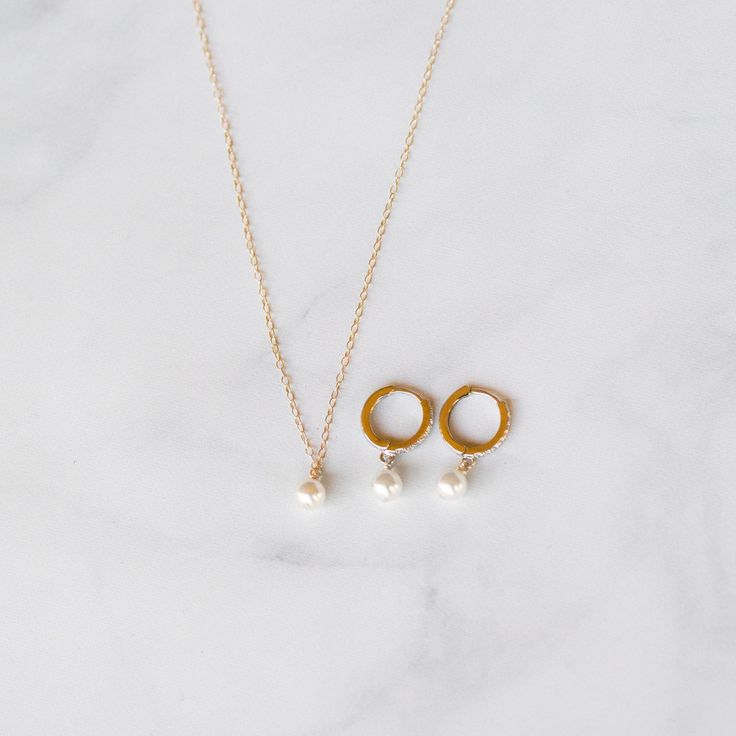 This exquisite handcrafted pearl necklace and huggie hoops gift set are a timeless fusion of elegance and style.  The necklace features a lustrous pearl delicately hanging on a chain, creating a classic yet modern look. Paired with my sleek Huggie diamond cz hoops adorned with subtle detailing, this set is the perfect balance of sophistication and versatility.  Elevate any outfit with this thoughtful and beautifully crafted ensemble, making it an ideal gift for those who appreciate the finer things in life. THE DETAILS:💜  14K Gold-filled Necklace & 14k Gold-Filled Hoops  14, 15, 16, 18, or 20 inches.  (14= small choker, 15= large choker, 16= collarbone, 18= standard, 20= long) Heavily Gold Plated Brass CZ Bee charm size 8mm (25mm=1 inch) Cubic Zirconia Stones  Option to be adjustable with Fine Jewelry Pearl Charm Pendant, Dangle Jewelry With Pearl Charm For Anniversary, Anniversary Pearl Charm Dangle Jewelry, Anniversary Dangle Jewelry With Pearl Charm, Fine Jewelry Dangle Pearl Charm, Fine Jewelry Pearl Charm Round Pendant, Delicate Pearl Charm Jewelry For Anniversary, Fine Jewelry With Round Pearl Charm, Fine Jewelry With White Pearl Charm