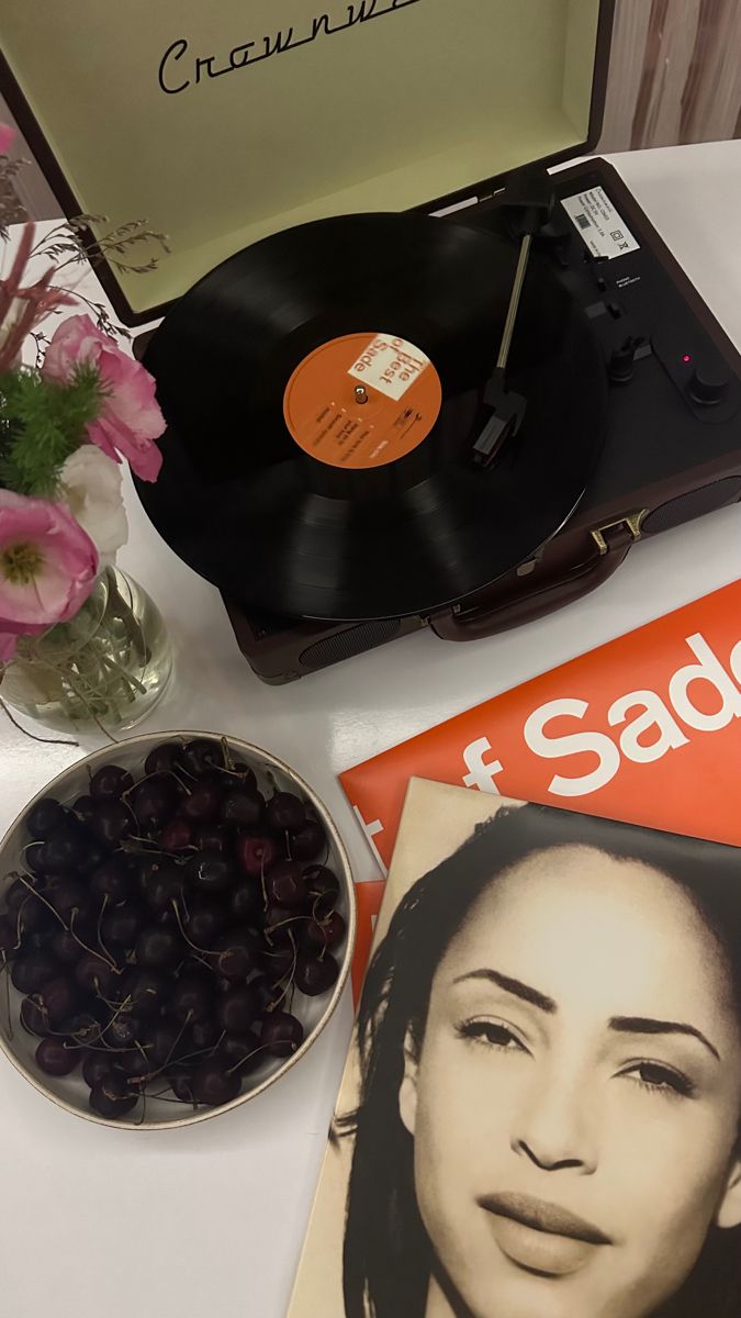 a record player, magazine and bowl of cherries on a table