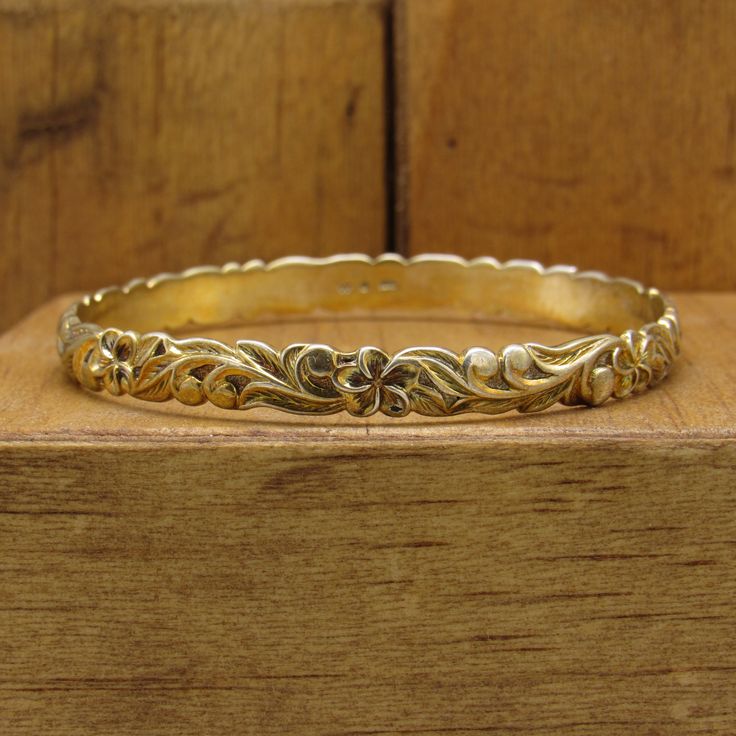 "Gold-tone sterling silver bangle bracelet. The design is flowers and leaves. 1/4\" wide. The diameter is 2 3/8\"Stamped 925. Good condition.  *The color on your screen may not reflect the actual stone color due to monitor variations.* BB-2" Etched Sterling Silver Bangle Bracelet For Wedding, Vintage Bangle Jewelry With Engraving Option, Vintage Bangle With Engraving Option, Etched Bangle Cuff Bracelet For Anniversary, Intricate Design Sterling Silver Gold Bangle, Stamped Sterling Silver Bangle For Wedding, Sterling Silver Stamped Bangle For Wedding, Vintage Gold Sterling Silver Bracelet For Weddings, Ornate Gold-colored Sterling Silver Bracelet