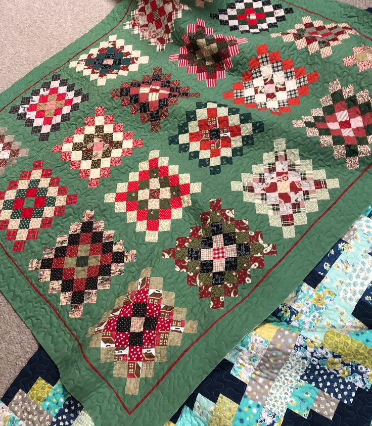 a quilted table topper on the floor with many different designs and colors in it