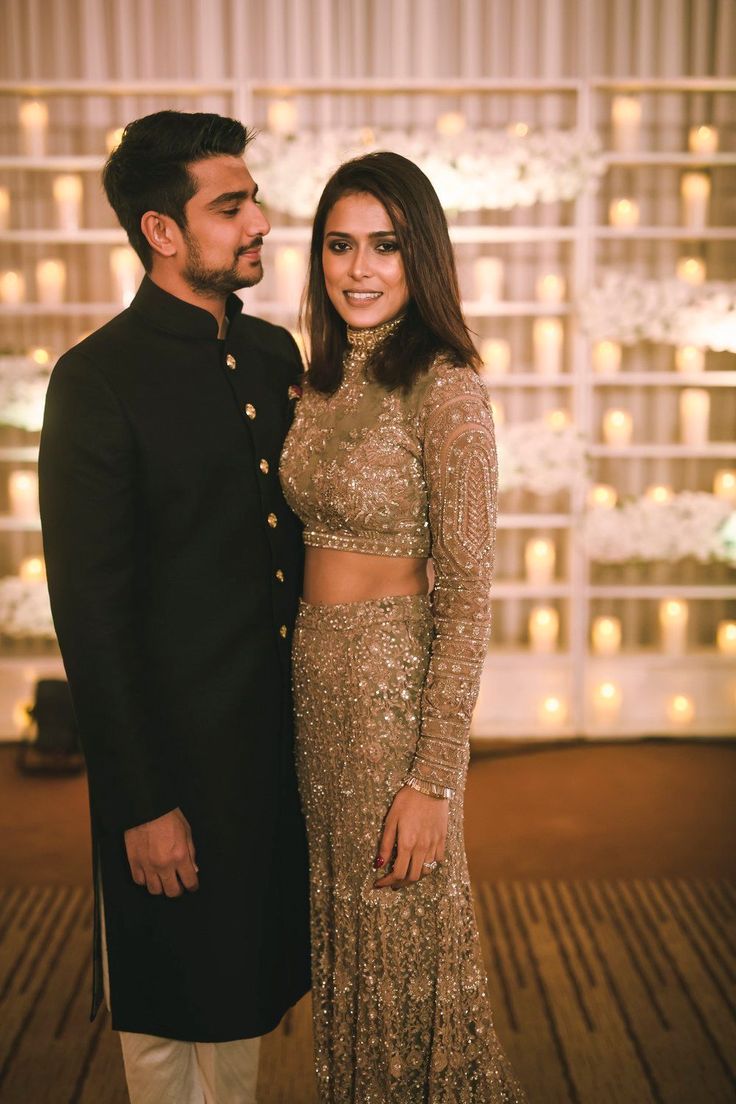 a man and woman standing next to each other in front of a wall with lights