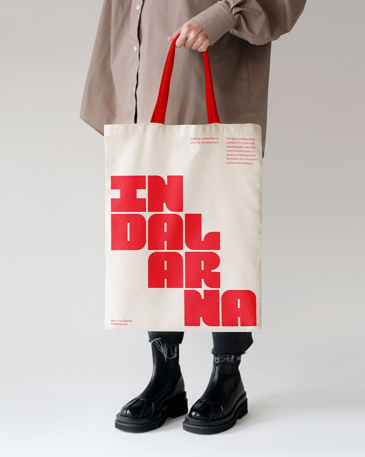 a person holding a red and white tote bag with the words ten dalr on it