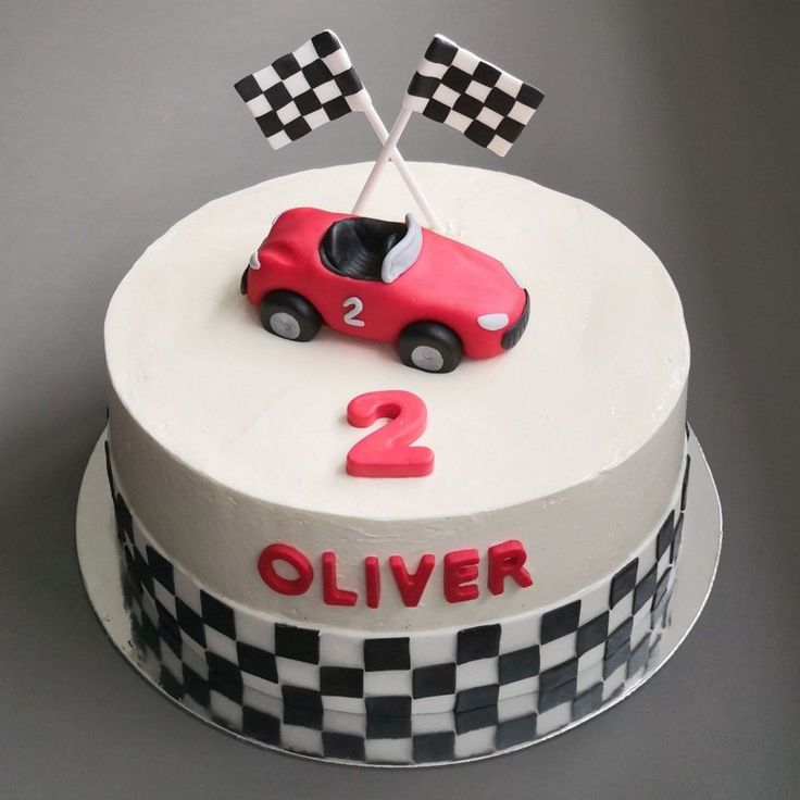 a birthday cake decorated with a racing car and checkered flag on the top tier