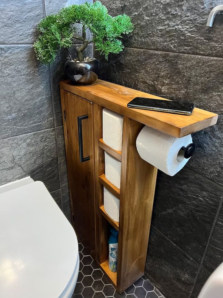 a bathroom with a wooden cabinet and toilet paper roll holder on the wall next to it