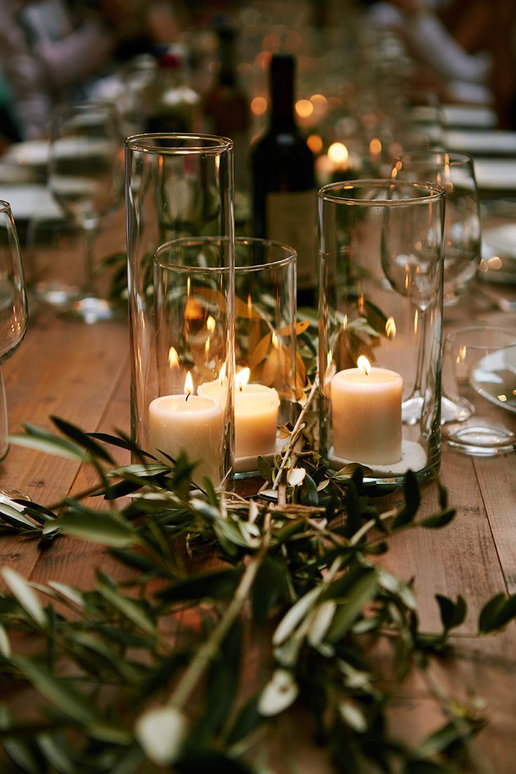 candles are lit on a table with greenery