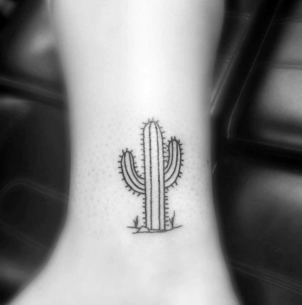 a small cactus tattoo on the ankle is seen in this black and white photo,