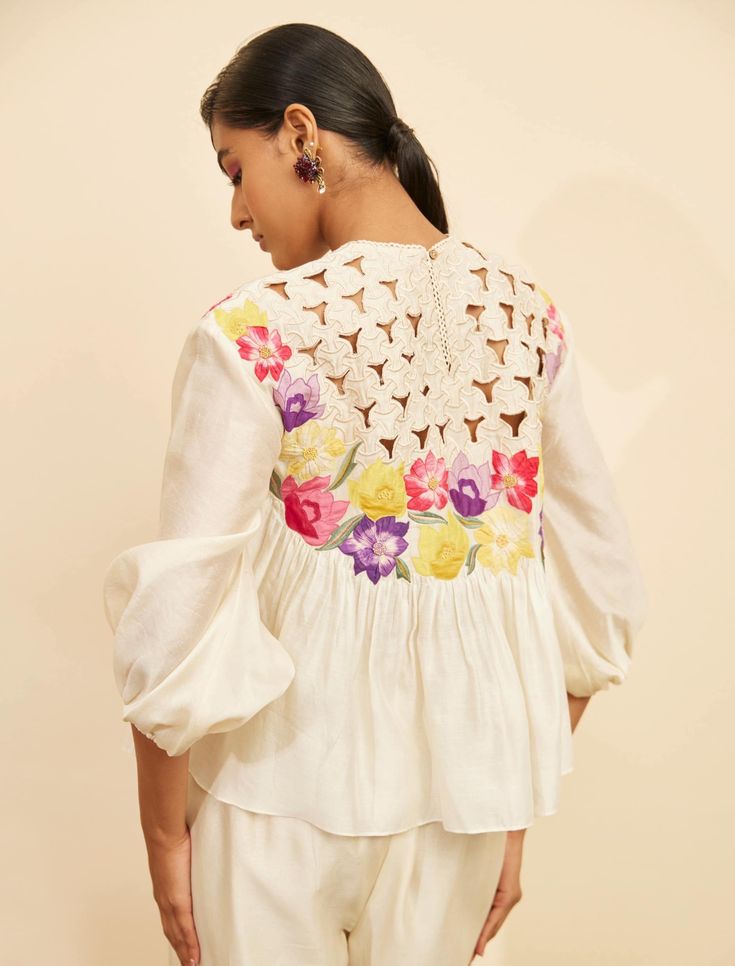 Editor's Note Featuring an ivory chanderi floral applique and cutwork top Note: Pant worn by model is for styling purposes and can be purchased separately. Color: Ivory Fabric: Chanderi Component: Top Occasion: Resort and daywear Care: Dry Clean Only About the Designer Chandrima celebrates diversity in cultures and craft forms creating ready-to-wear women wear for the urban woman of today. The brand embodies the idea of Indian handloom and craft merged with an international style. Label Chandrim Cream Chikankari Embroidered Summer Tops, Feminine Summer Sets With Chikankari Embroidery, Cream Tops With Chikankari Embroidery For Summer, Cream Summer Tops With Chikankari Embroidery, Summer Cream Tops With Chikankari Embroidery, Bohemian Off White Summer Sets, Off White Bohemian Summer Sets, Chic White Embroidered Set, White Tops With Resham Embroidery