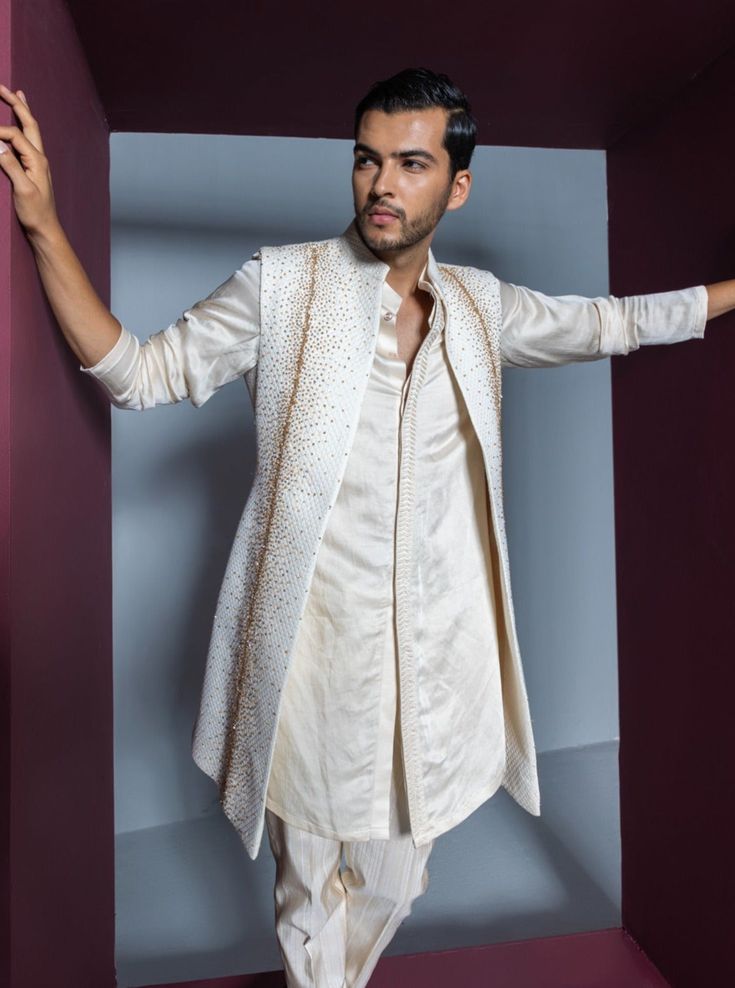 Crystal Shrug Set - Contrast by Parth An ensemble featuring a shrug adorned with a glistening array of gold crystals, paired elegantly with a kurta and pants. Included in purchase: Shrug, Kurta and Pants Product Specification Color: Ivory (can be customized) Fabric: Jacquard Occasion: Formal Event, Wedding, Bridal, Reception Style: Shrug Set Designer: Contrast by Parth Care: Dry Clean Only Work: Hand Embroidered ( Variation in color, fabric & detail is possible. Model images are only representative.) This can be customized in any color, size or style of your choice. ** Please contact us at 19257910374 for customization options. Delivery time for customized outfits is 4 - 6 weeks. Work Crystals, Kurta And Pants, Gold Crystals, Add Sleeves, Indian Wedding Wear, Wear Store, Kurta With Pants, Band Collar, Jacquard Fabric