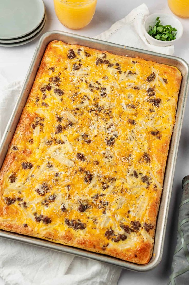 a square casserole with cheese and meat in it on a white tablecloth