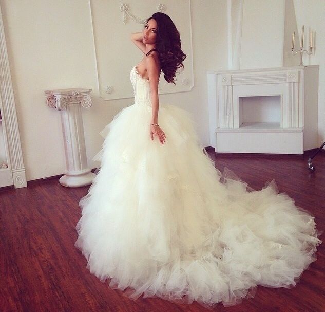 a woman in a white wedding dress standing on a wooden floor next to a fireplace