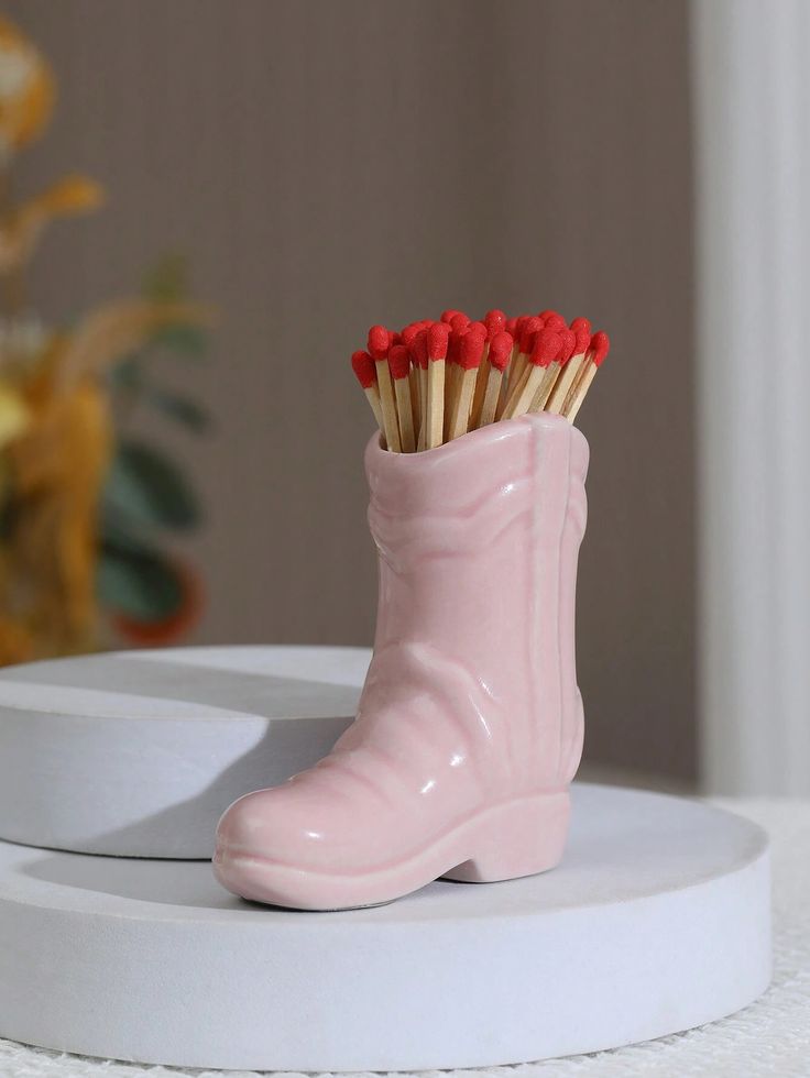 a pink boot with matches sticking out of it sitting on top of a white table