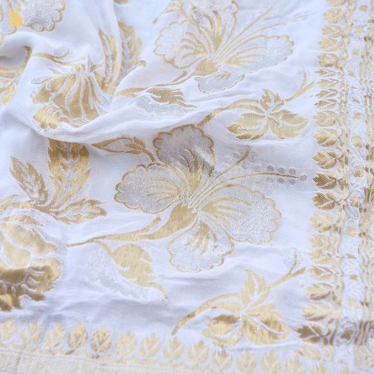 an embroidered white and gold cloth with floral design on the edges, close up view