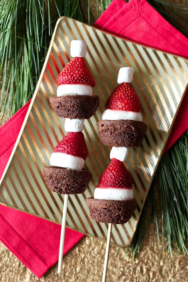 three chocolate cupcakes decorated with strawberries and marshmallows on a plate