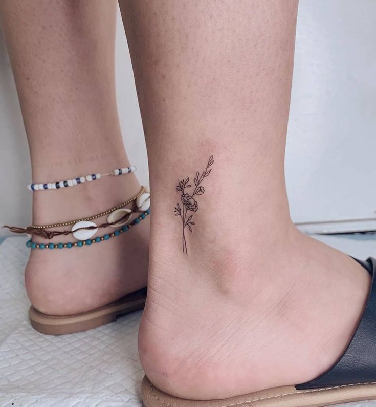 a woman's foot with a small flower tattoo on the left side of her ankle