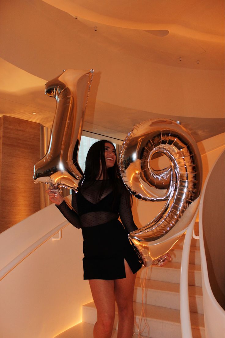 a woman holding some balloons in her hand and standing on the stairs at an event