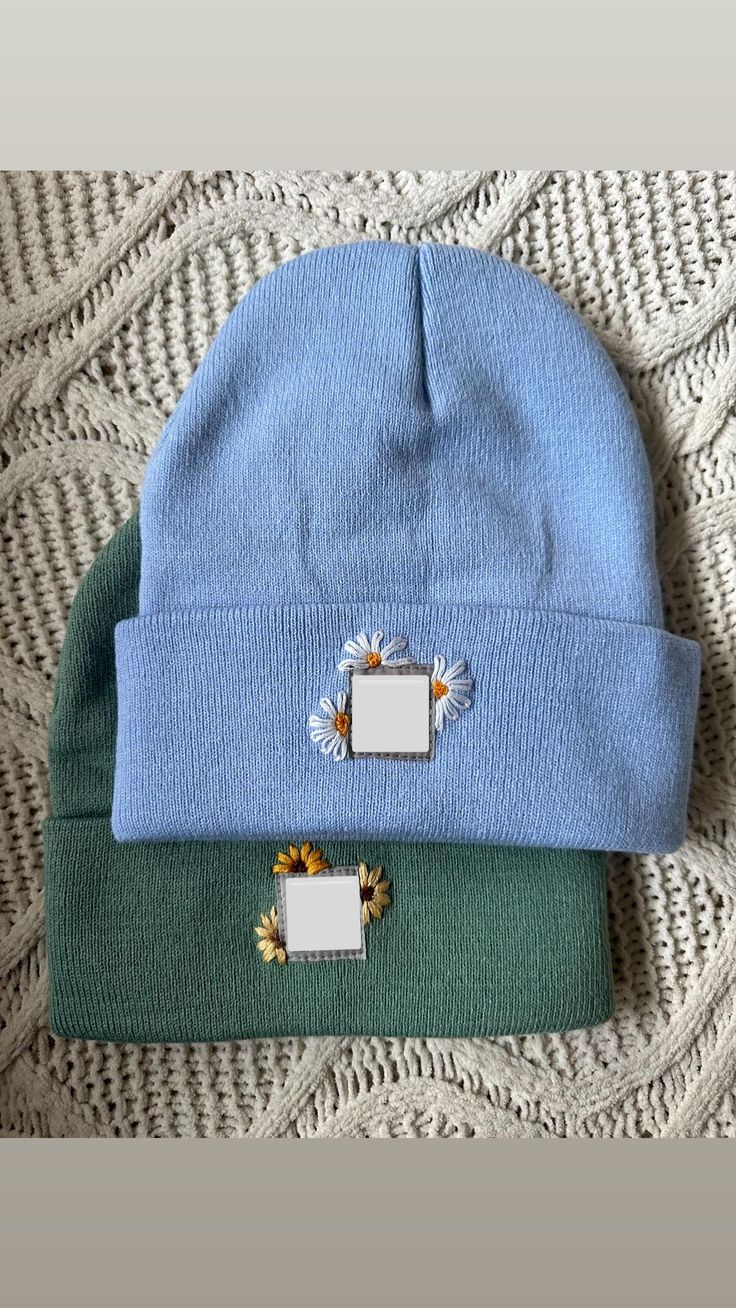 two beanies sitting on top of a bed next to each other, one blue and the other green