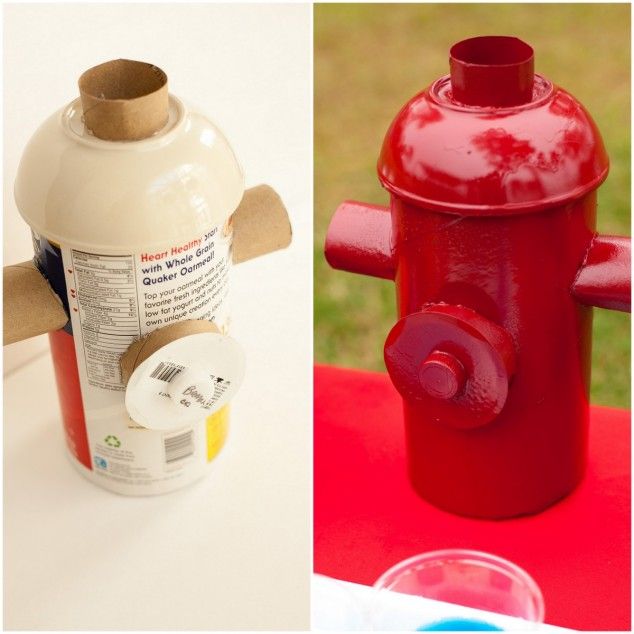 a red fire hydrant sitting on top of a table next to a plastic cup