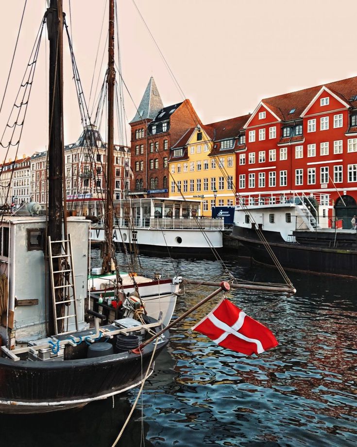 a boat in the water near some buildings and a flag on it's mast