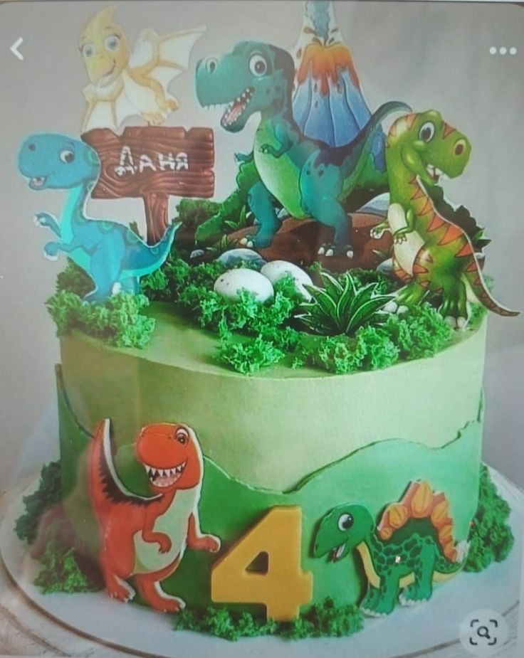 a birthday cake decorated with dinosaurs and grass