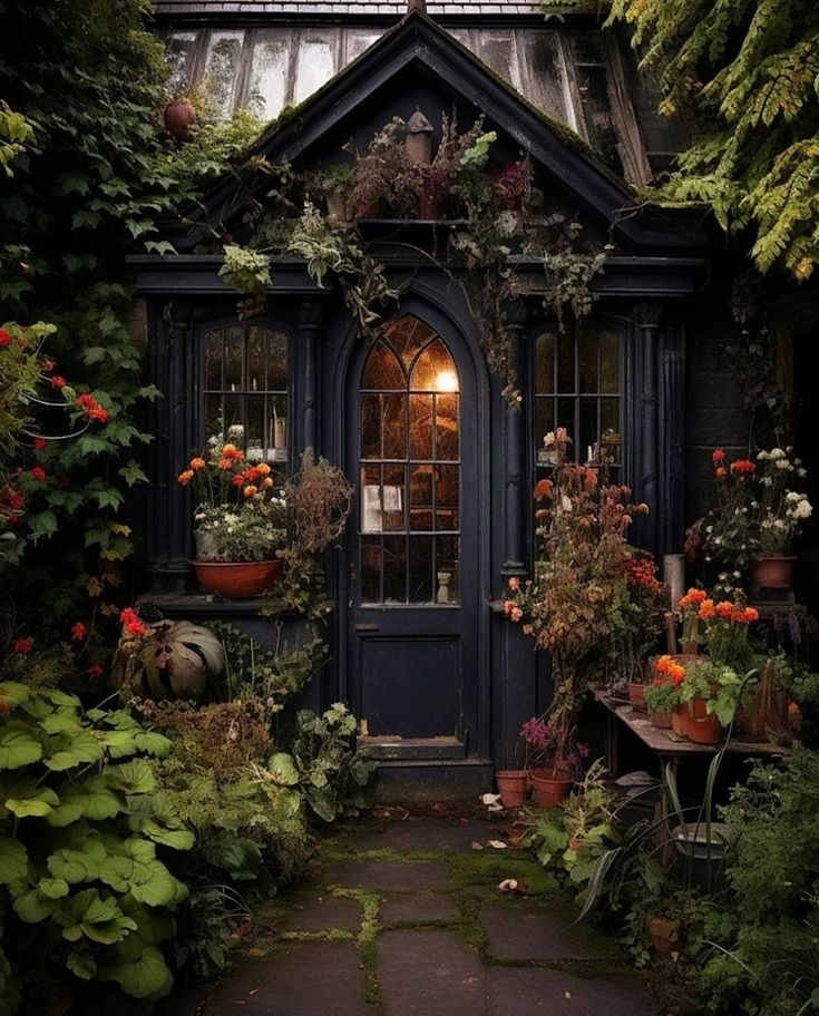 an old house with plants and potted flowers on the front door, surrounded by greenery