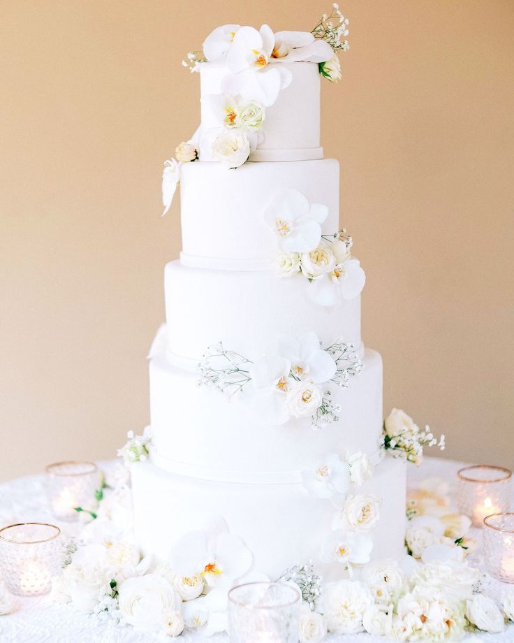 a wedding cake with white flowers and candles