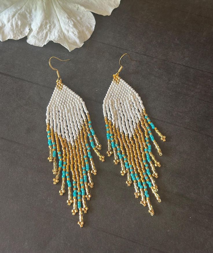 the beaded fringe earrings are hanging from gold - plated hooks with turquoise beads